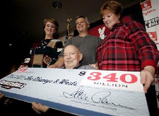 Bob Chaney, seated, is joined by, from background left, his wife, Frances Chaney; son-in-law, Steve West; and daughter, Carolyn West; as they hold a ceremonial $340 million Powerball check at the Oregon Lottery Commission.